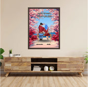 Personalized couple framed canvas of two people sitting together on a bench beneath blooming pink spring flowers, with a custom romantic quote above them and their names displayed at the bottom — LOVECOUPLET