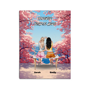Personalized couple canvas of a lesbian couple sitting together on a bench beneath blooming pink spring flowers, with a custom romantic quote above them and their names displayed at the bottom — LOVECOUPLET
