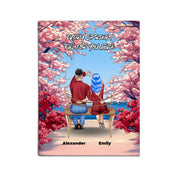 Personalized couple canvas of two people sitting together on a bench beneath blooming pink spring flowers, with a custom romantic quote above them and their names displayed at the bottom — LOVECOUPLET
