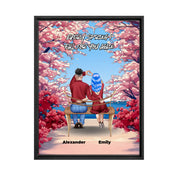 Personalized couple framed canvas of two people sitting together on a bench beneath blooming pink spring flowers, with a custom romantic quote above them and their names displayed at the bottom — LOVECOUPLET
