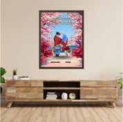 Personalized couple framed canvas of two people sitting together on a bench beneath blooming pink spring flowers, with a custom romantic quote above them and their names displayed at the bottom — LOVECOUPLET