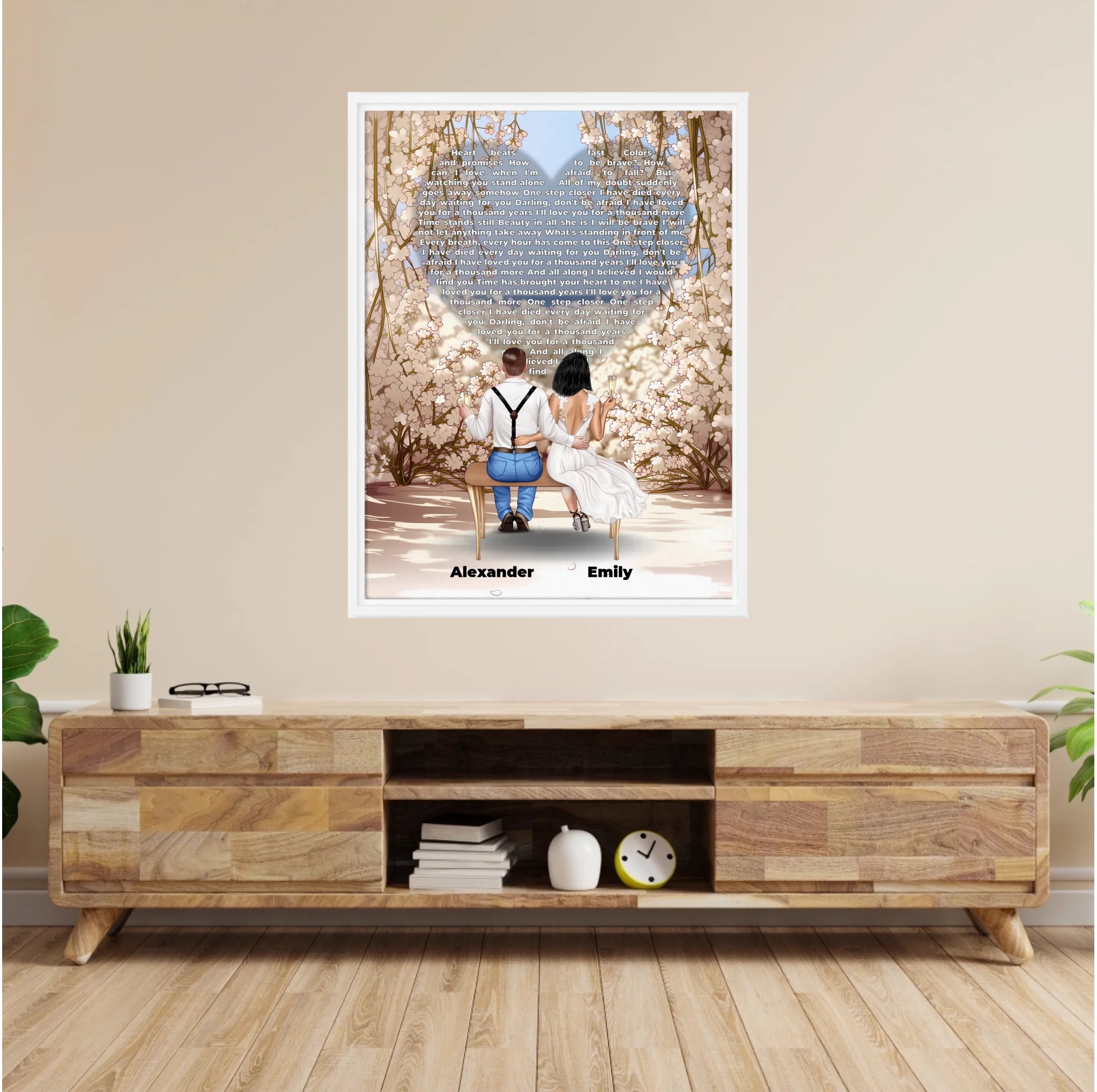 Personalized wedding couple framed canvas of a bride and groom sitting on a bench beneath a blooming floral garden arch, with custom lyrics shaped into a heart above them and their names at the base of the scene — LOVECOUPLET