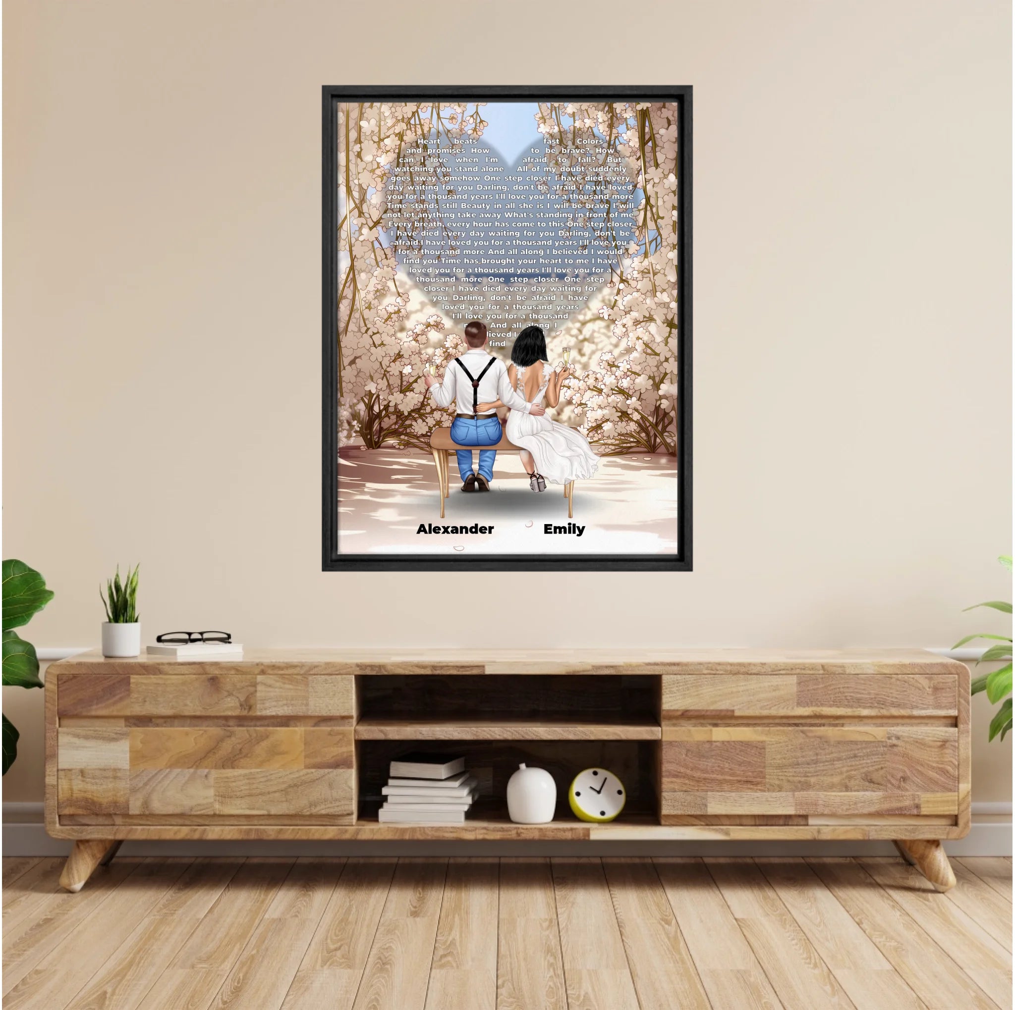 Personalized wedding couple framed canvas of a bride and groom sitting on a bench beneath a blooming floral garden arch, with custom lyrics shaped into a heart above them and their names at the base of the scene — LOVECOUPLET