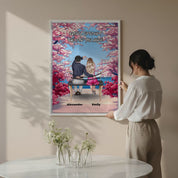 Personalized couple canvas of two people sitting together on a bench beneath blooming pink spring flowers, with a custom romantic quote above them and their names displayed at the bottom — LOVECOUPLET