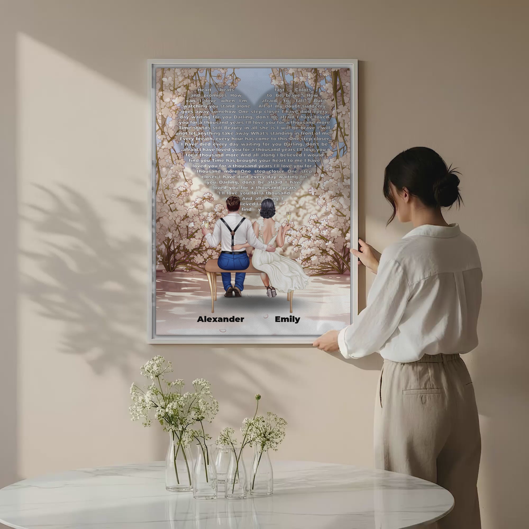 Personalized wedding couple canvas of a bride and groom sitting on a bench beneath a blooming floral garden arch, with custom lyrics shaped into a heart above them and their names at the base of the scene — LOVECOUPLET