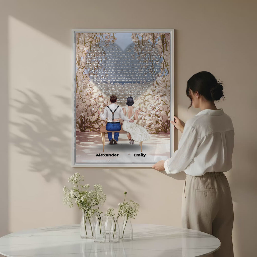 Personalized wedding couple canvas of a bride and groom sitting on a bench beneath a blooming floral garden arch, with custom lyrics shaped into a heart above them and their names at the base of the scene — LOVECOUPLET