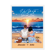 Personalized couple framed canvas of two people sitting together on a beach picnic blanket at sunset, with a custom romantic quote above the ocean and their names written in the sand — LOVECOUPLET