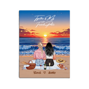 Personalized lesbian couple canvas of two people sitting together on a beach picnic blanket at sunset, with a custom romantic quote above the ocean and their names written in the sand — LOVECOUPLET