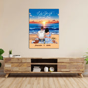 Personalized couple canvas of two people sitting together on a beach picnic blanket at sunset, with a custom romantic quote above the ocean and their names written in the sand — LOVECOUPLET